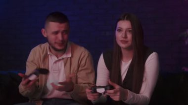 Genç çift evde video oyununun tadını çıkarıyor. Aile oturma odasında kanepede otururken oyun konsolu oynuyor. Sinirli erkek arkadaş, kız arkadaşına oyun alanını doğru kullanmayı öğretiyor. Yüksek