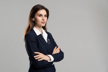 Elektrikli mavi takım elbiseli, kolları çapraz duran, resmi bir ceket ve kolları katlanmış bir gömlek giyen bir kadın..