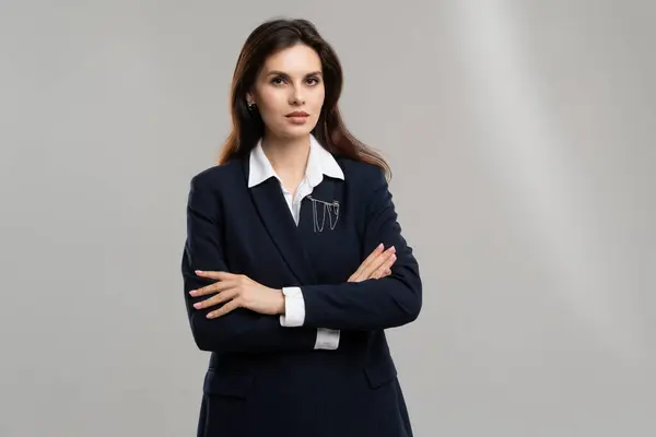 Resmi giyinmiş bir kadın, spor ceket ve gömlek de dahil, kollarını iş elbisesine bağlamış duruyor..