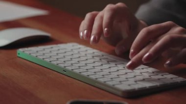 Masadaki iş yerinde bir kadın oturuyor. Kadın eli kablosuz bir klavyeye mesaj yazar ve bir bilgisayar faresini kaydırır. Kapatın. Çekim modu görüntüsü yok. Yüksek kalite 4k görüntü
