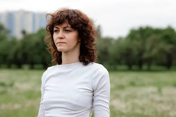 Güzel bayan parkta spor paspası kullanarak yoga yapıyor. Rahat kız sabahları meditasyon yapıyor. Yetişkin spor kadını Lotus doğanın arka planında poz veriyor. Yüksek kalite fotoğraf