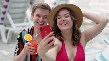 İki arkadaş rahatlatıcı bir tatilin tadını çıkarıyor, mutlu anları selfie ve havuz başında kokteyllerle yakalıyorlar..