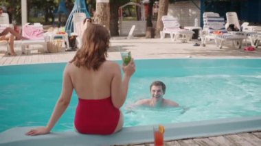 Romantik bir kaçamak için güzel bir havuz ortamında bir çift ferahlatıcı içecekler ve dinlenmenin tadını çıkarıyor.