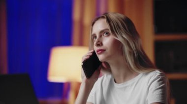 Duygularını ifade eden genç bir kadın rahat bir ofis ortamında telefon görüşmesi yapıyor.