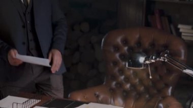 Masasında evrak ve ofis düzeninde lambayla çalışan takım elbiseli profesyonel bir işadamı..