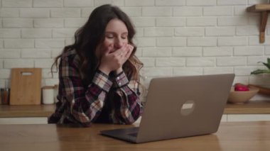 Mutfakta dizüstü bilgisayarından bir şey izleyen bir kadın internete bağlı kalarak çeşitli tepkiler gösteriyor.