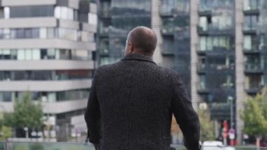 Bir iş adamının balkonda dikiz aynasından modern bir şehir manzarasına bakarken camdan binalar....