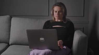 Bir kadın evinde dizüstü bilgisayarında çalışıyor, uzaktan çalışmayı, odaklanmayı ve üretkenliği simgeliyor.