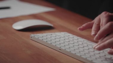 Bir kişi modern bir ofiste kablosuz bir klavye ve fare kullanıyor, karmaşık eylemlere odaklanıyor