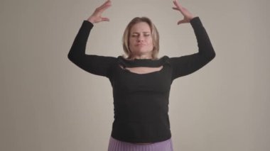 Meditasyon ve rahatlama pratiği yapan bir kadın gözleri kapalı poz verir, farkındalık teknikleri gösterir.