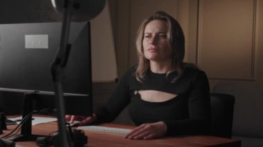 Ofis ortamında bilgisayarının başında özenle çalışan profesyonel bir kadın odaklanma ve kararlılık gösteriyor..