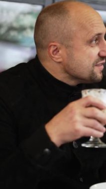 Rahatlamak ve gençleşmek için huzurlu atmosferine dalmış, rahat bir kafede içkinin tadını çıkaran bir adam.