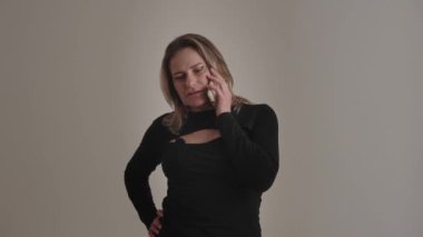 Telefonla konuşan bir kadın izole edilmiş bir ortamda endişeli görünüyor. Profesyonel kıyafet, gayri resmi ortam..