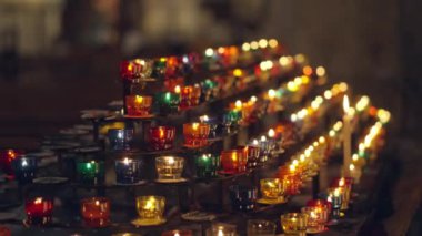 Sönük bir kilisedeki tezgahta dizilmiş renkli adak mumları durgun bir ortam yaratıyor..