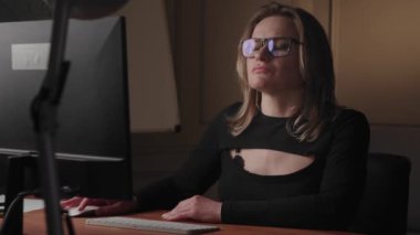 Modern ofis ortamında geç saatlere kadar çalışan gözlüklü profesyonel bir kadın..