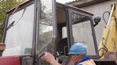 Güvenlik teçhizatı olan bir inşaat işçisi bir şantiyede ağır makineler çalıştırıyor ve çalışmaya hazırlanıyor.