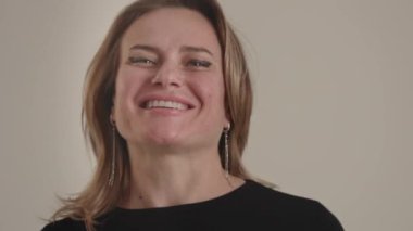 Dost canlısı, gülümseyen ve olumlu genç Amerikalı ya da Avrupalı sarışın modelin yakın çekimleri, reklam için stüdyoda poz veriyor ya da bej arka plana karşı profesyonel portföy. Kameraya bak.