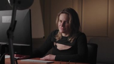 İş kadını gece geç saatlere kadar çalışıyor, odaklanmış ve ciddi, bilgisayar kullanırken çeşitli duygular gösteriyor..