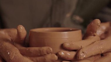 Çömlekçi bir adam oğluyla birlikte çalışır. Baba ve çocuk büyük bir kase ya da çömleğe şekil verirler. Ebeveyn sahibi erkek ellerini örter ve kendi toprak malzemelerini yapmasına yardım eder. Kalıtsal el işi ve nakil
