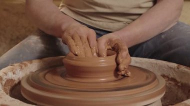 Çömlekçi bir adamın elleri dönen çömlek çarkında kil testi yapar. Bir zanaatkar bir atölyede oturur ve çalışır, el yapımı toprak malzemesi üretir. Hobi olarak el işi kavramı ve...