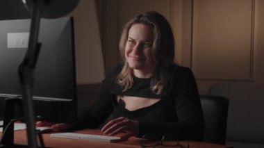 Modern ofis ortamında bilgisayarında çalışan kendine güvenen bir kadın profesyonelliğini ve odaklanmasını gösteriyor..