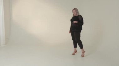 Şık ve modaya uygun bir model zarif bir şekilde modern modayı sergiliyor ve güzel minimalist bir stüdyo ortamında poz veriyor.