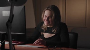 Profesyonel bir ofiste, neşeli bir iş kadını bilgisayarında geç saatlere kadar çalışır, özveri ve odaklanma gösterir.