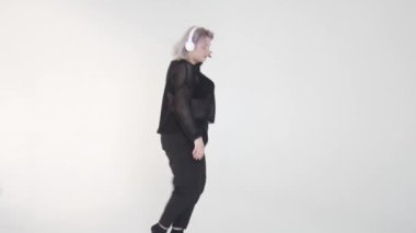 Şık ve şık bir kadın kulaklık takıp, kendine güvenini ve tarzını sergileyerek neşeyle dans eder.