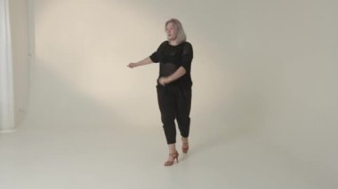 Şık siyah kıyafetli yetenekli bir dansçı canlı, canlı bir stüdyo ortamında dinamik hareketler sergiliyor.