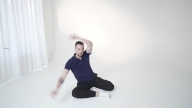 Minimalist bir stüdyoda, bir dansçı zarif bir hareket ve vücut duruşu ile derin bir duygu dizisi ifade eder.