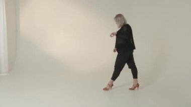 Şık ve modern bir model şık bir minimalist stüdyo ortamında yürürken zarafet ve zarafet sergiler.