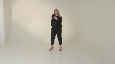 Şık, minimalist bir stüdyo ortamında poz veren şık bir kadın, zarafetini sergiliyor.