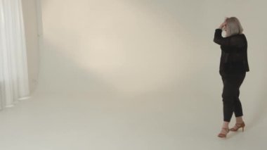 Şık gri saçlı bir manken modern, minimalist stüdyo alanına güvenini sergiliyor.