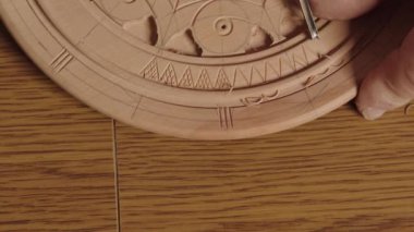 Yetenekli bir zanaatkar titizlikle dairesel bir ahşap deseni büyük bir özenle ve titizlikle oyuyor.
