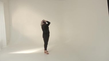 Zarif ve zarif bir model parlak, minimalist bir stüdyo ortamında büyüleyici bir poz veriyor.