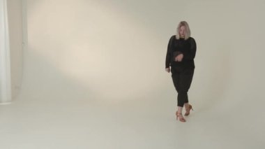 Kendine güvenen bir kadın zarif, minimalist bir stüdyoda modern modayı güzel bir şekilde sergiliyor.
