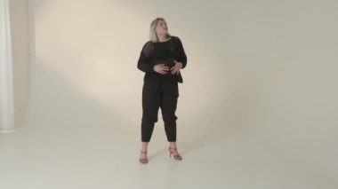 Minimalist bir stüdyoda şık bir kadın şık siyah elbiseler giyerek zarafetini sunar.