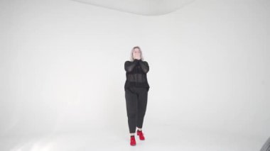 Güzel tasarlanmış, minimalist bir stüdyoda, modern modayı sergileyen şık bir model kendine güvenerek poz verir.