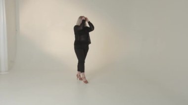 Dengeli ve kendinden emin bir model, şık ve şık bir kıyafeti canlı, minimalist bir stüdyo alanında ustalıkla sergiliyor.