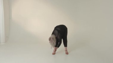 Yetenekli bir dansçı minimalist bir ortamda esnekliğini ve zarafetini güzel bir şekilde sergiliyor.