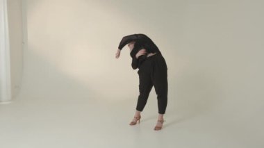 Yetenekli bir dansçı gururla minimalist stüdyo ortamında eşsiz ve anlamlı bir poz sergiler.