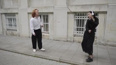 Bu ilgi çekici video canlı şehir yaşamını gösteriyor. İki kadın geziniyor, bir çift sohbet ediyor ve neşeli anlar, eğlenceli bir dans da dahil.