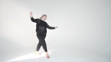 Yetenekli bir dansçı, minimalist bir stüdyoda zarif ve enerjik hareketler sergiliyor.