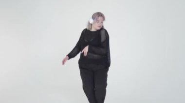 Modaya uygun bir insan şık siyah giysiler içinde zarif bir şekilde dans eder. Modern tarzını göstererek.