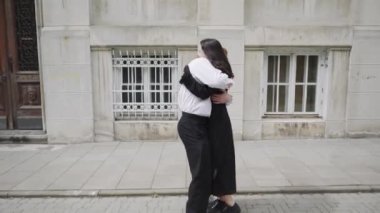 Canlı bir video, kaldırımda tutkulu bir şekilde dans eden bir adam ve kadını, iki kadın eşliğinde, neşe, sevgi ve dostluk gösterirken gösteriyor.