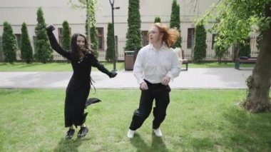 Bu canlı video, iki kadının neşeyle frizbi oynadığı güneşli bir park gününü gösteriyor. Birkaç dans, eğlence, arkadaşlık ve doğa.
