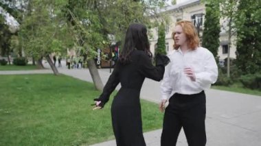 Manzaralı bir parkta, iki kadın güler, bir çift birbirini sever, diğeri el ele tutuşur, bağın sembolü, neşeli bir dansla sonuçlanır.