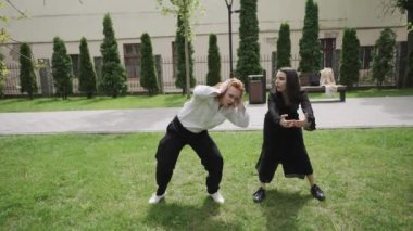 Bu video, bir parkta neşeli açık hava dansları sergiliyor. İki kadın ve bir erkek, canlı bir manzaranın ortasındaki bağlantıyı kutluyor.