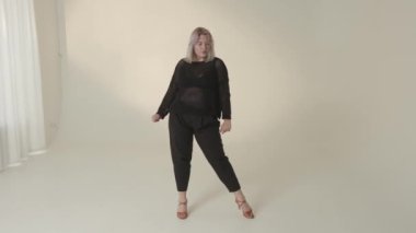 Kendine güvenen bir model şık topuklularla tamamlanmış modaya uygun siyah giysileri gururla sergiler.