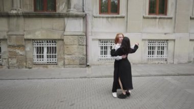 Canlı bir video, bir adam ve kadını, bir şehir caddesinde neşeli bir şekilde dans ederken, canlı bir enerji ve arkadaşlık teması yakaladığını gösteriyor.